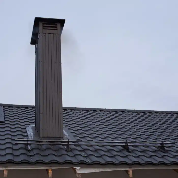 Conduit de cheminée installé sur une toiture en métal à Rouen.